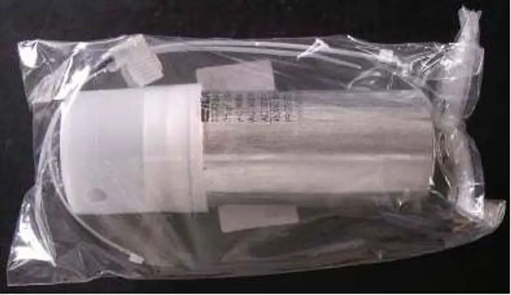 Kondensator in transparentem Verpackungsmaterial; die Marke Remeha ist sichtbar. Der Kondensator ist aus Metall mit einem Anschlusskabel und scheint für elektrische Anwendungen verwendet zu werden.